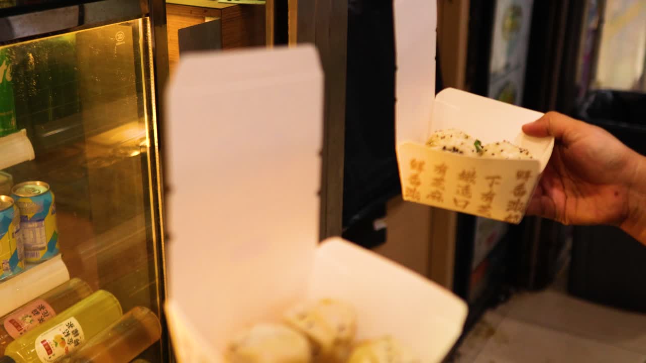 Person opening box of fried buns at stall