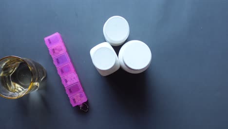 caja de pastillas, frascos de medicamentos y un vaso de agua