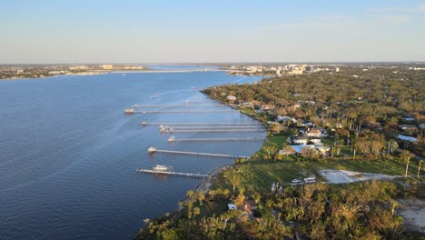 aerial view of manatee river with damaged docks, fallen trees, and power restoration efforts. crane down