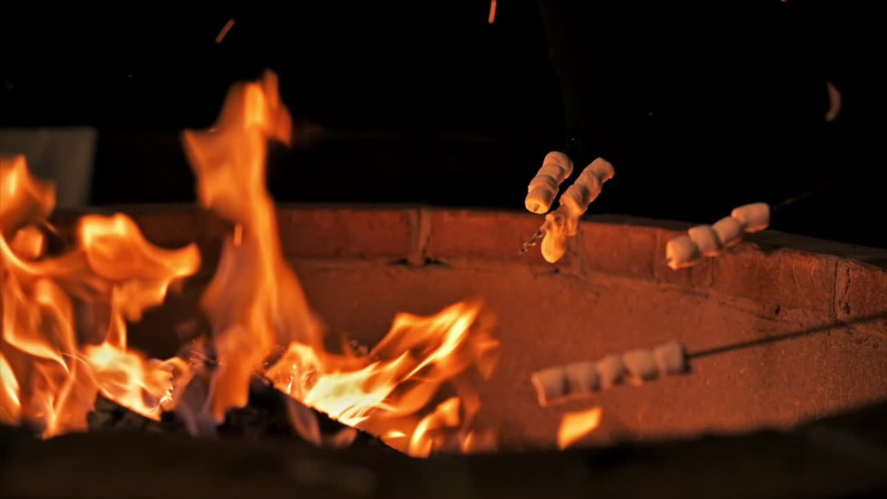 A group of young friends near a campfire at glamping, night. Frying marshmallow. Slow motion