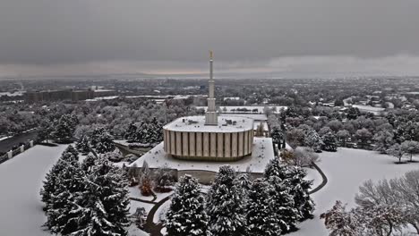 Drone-circles-around-backside-of-Provo-LDS-Mormon-Temple-with-Provo,-Orem,-Vineyard-off-in-distance-of-Utah