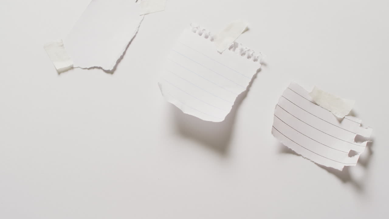 video de un primer plano de tres trozos de papel con espacio de copia pegado en un fondo blanco
