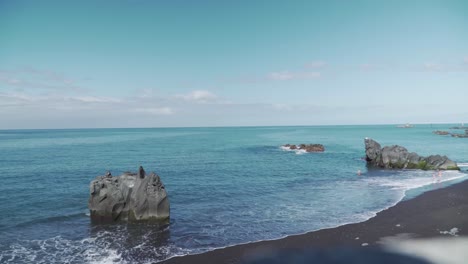 volcanic black sand beach with people swimming