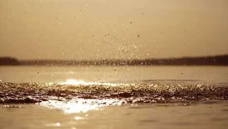 silhouette of a boy in lake with many drops of water on him. splashing of water on a boy in the river. mother and her children enjoying the time together in water at sunset.