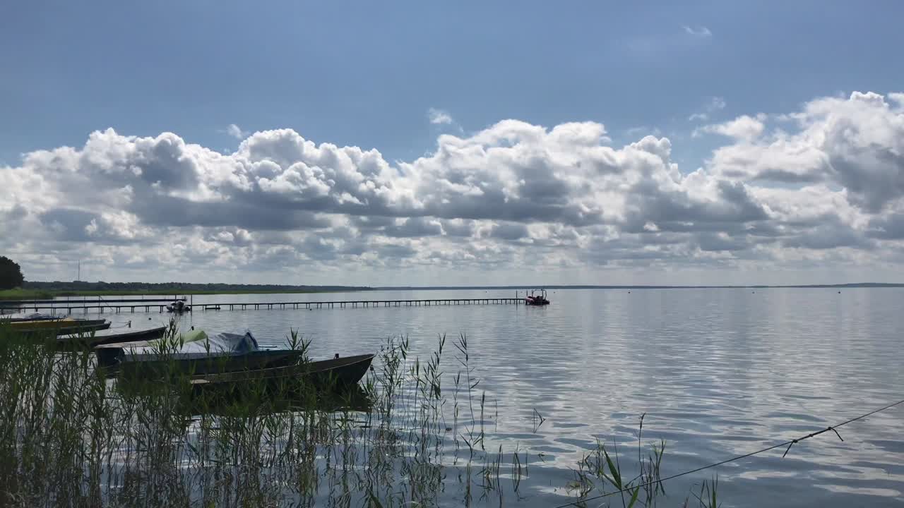 담수 호수에서 빛 날씨, 파도에서 바위 배와 요트, 푸른 하늘에서 울창한 구름.