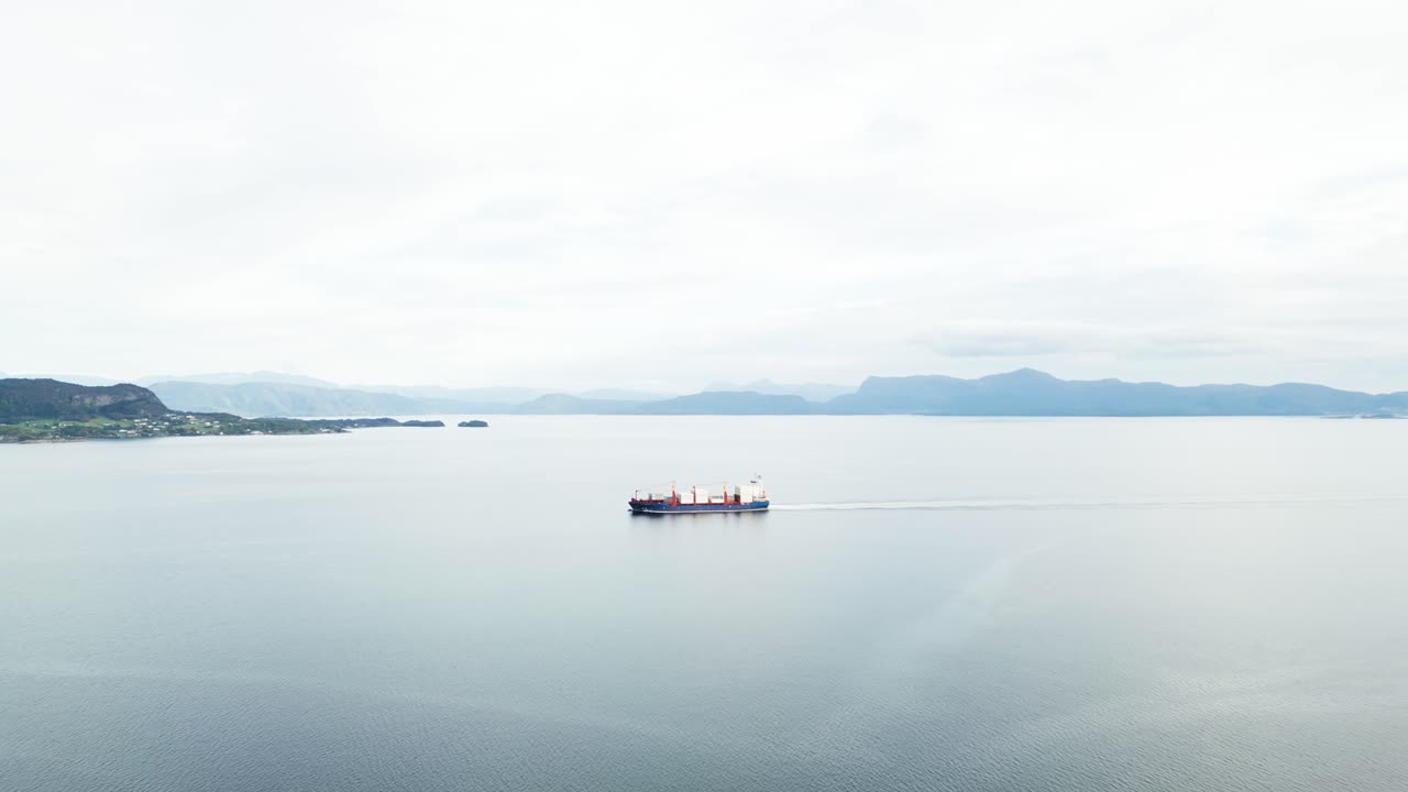 A cargo ship sails through calm waters with mountainous shores in the distance. A minimalist landscapeCargo ship