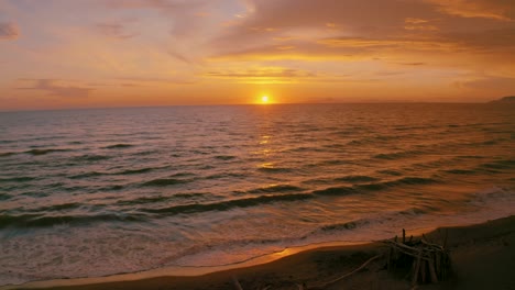 imágenes aéreas de drones de la puesta de sol en una playa de arena a la orilla del mar en el icónico parque natural maremma en toscana, italia, con un espectacular cielo nuboso y tipis de madera a lo largo de la playa vacía