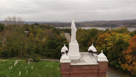 una vista aérea de una estatua de la virgen maría en la parte superior de una iglesia católica en el norte del estado, ny