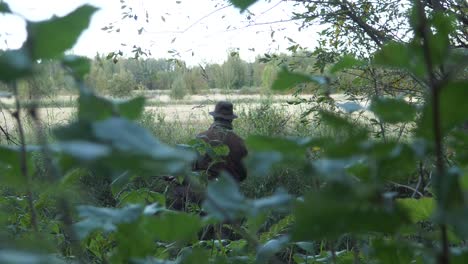 cazador escondido en hierba verde y follaje, cámara lenta cinematográfica con poca profundidad de campo