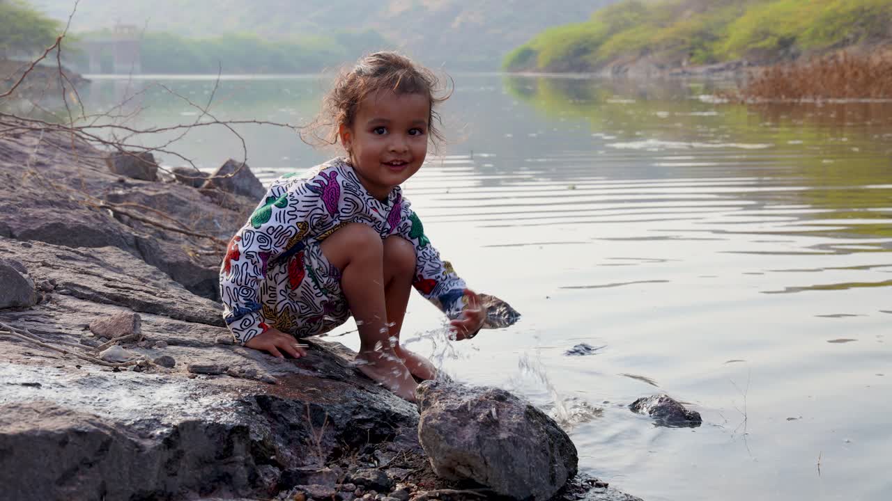 湖畔の水辺で遊ぶかわいいインド人の幼児。
