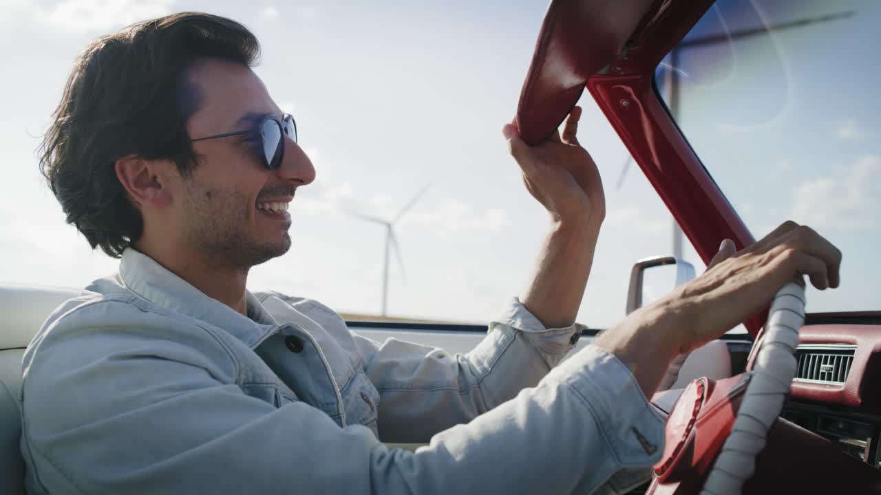 video de vista lateral de un hombre feliz conduciendo un elegante coche rojo