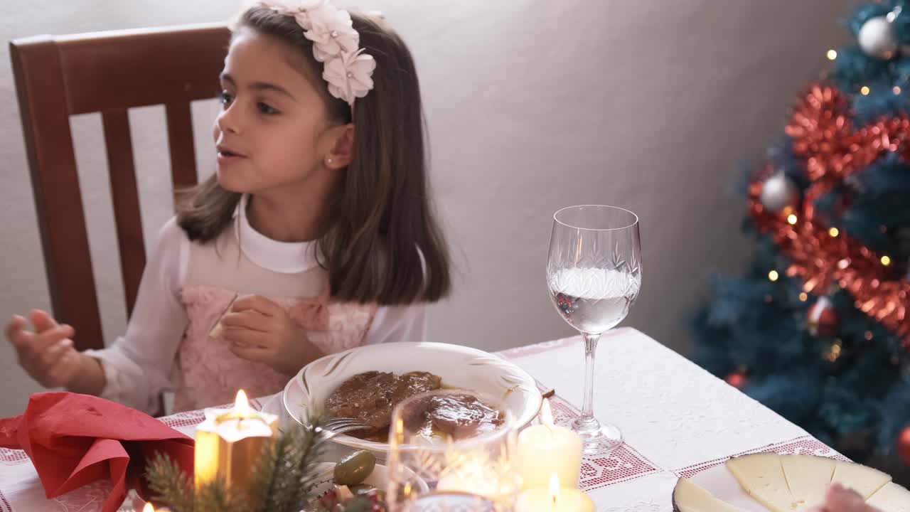 Girl dressed in white eating distracted during Christmas lunch