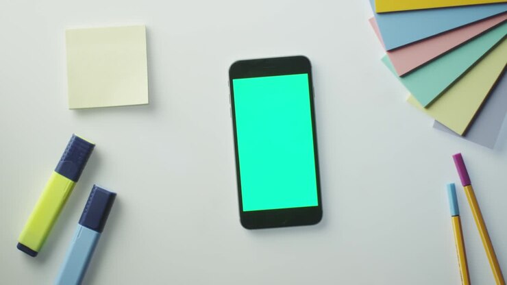 Designer che usa uno smartphone con schermo verde in modalità verticale. Vista dall'alto