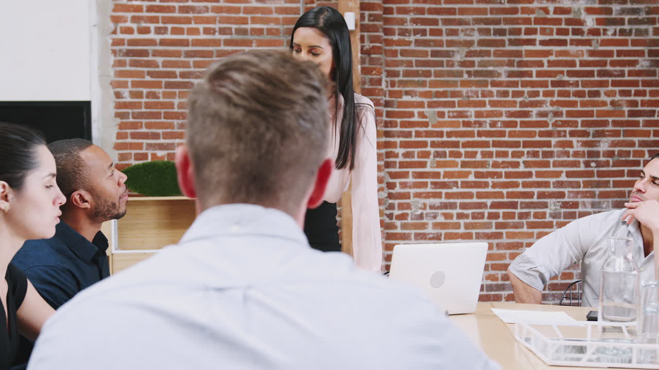 joven mujer de negocios de pie y líder de la reunión de la oficina alrededor de la mesa