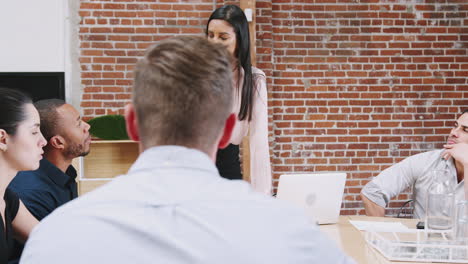 joven mujer de negocios de pie y líder de la reunión de la oficina alrededor de la mesa