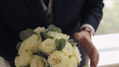 Groom-with-wedding-bouquet-in-his-hands-at-home-preparing-to-go-to-bride,-close-up-slow-motion