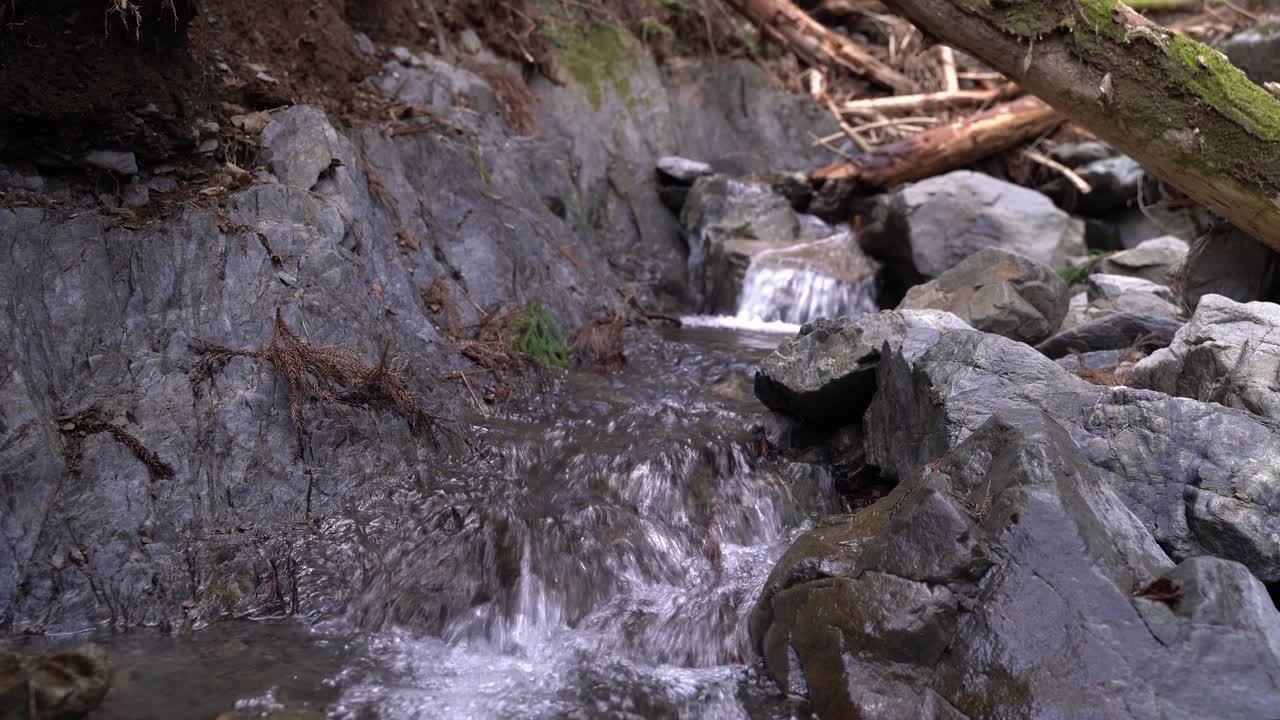 Crystal Clear Water Flowing Through The Large Rocks Under The Summer Weather