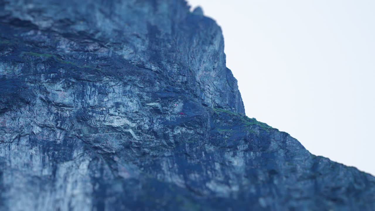 두 명의 스카이 다이버가 절벽에서 뛰어내리고 천천히 미끄러져 내려갑니다.