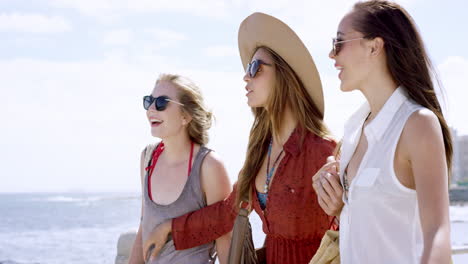 three young women tourists on summer vacation walking on beach promenade