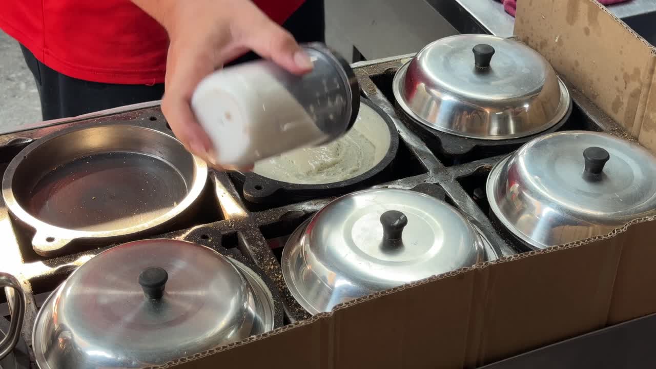 A close-up of a vendor making peanut pancakes, aka apam balik, min jiang kueh or tai kau min on a hawker street food stall in Penang, Malaysia