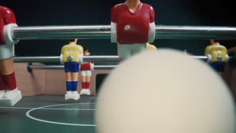 Vista-A-Nivel-De-Mesa-De-Jugadores-De-Futbolín-Pateando-La-Pelota.