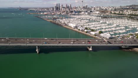 traffic on auckland harbour bridge, aerial view of royal yacht squadron club and cityscape with sky tower