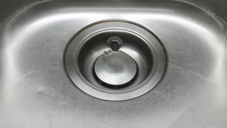 el agua se drena en un fregadero de cocina de metal cerca de la toma de detalle