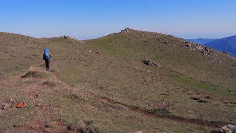 backpack hiker walks on remote mountain ridge trail on windy day