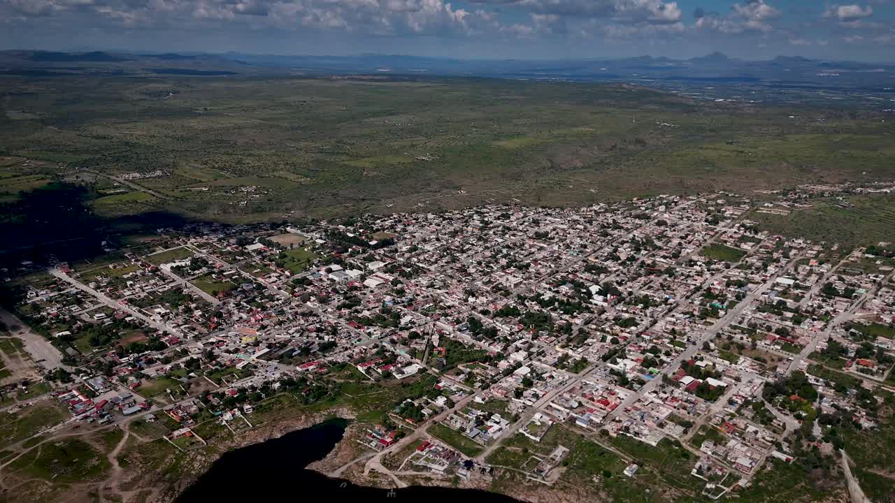 Aerial drone footage on a sunny day capturing the scenic Magic Town of San José de Gracia, surrounded by mountains and nature in Aguascalientes, Mexico — a peaceful rural landscape