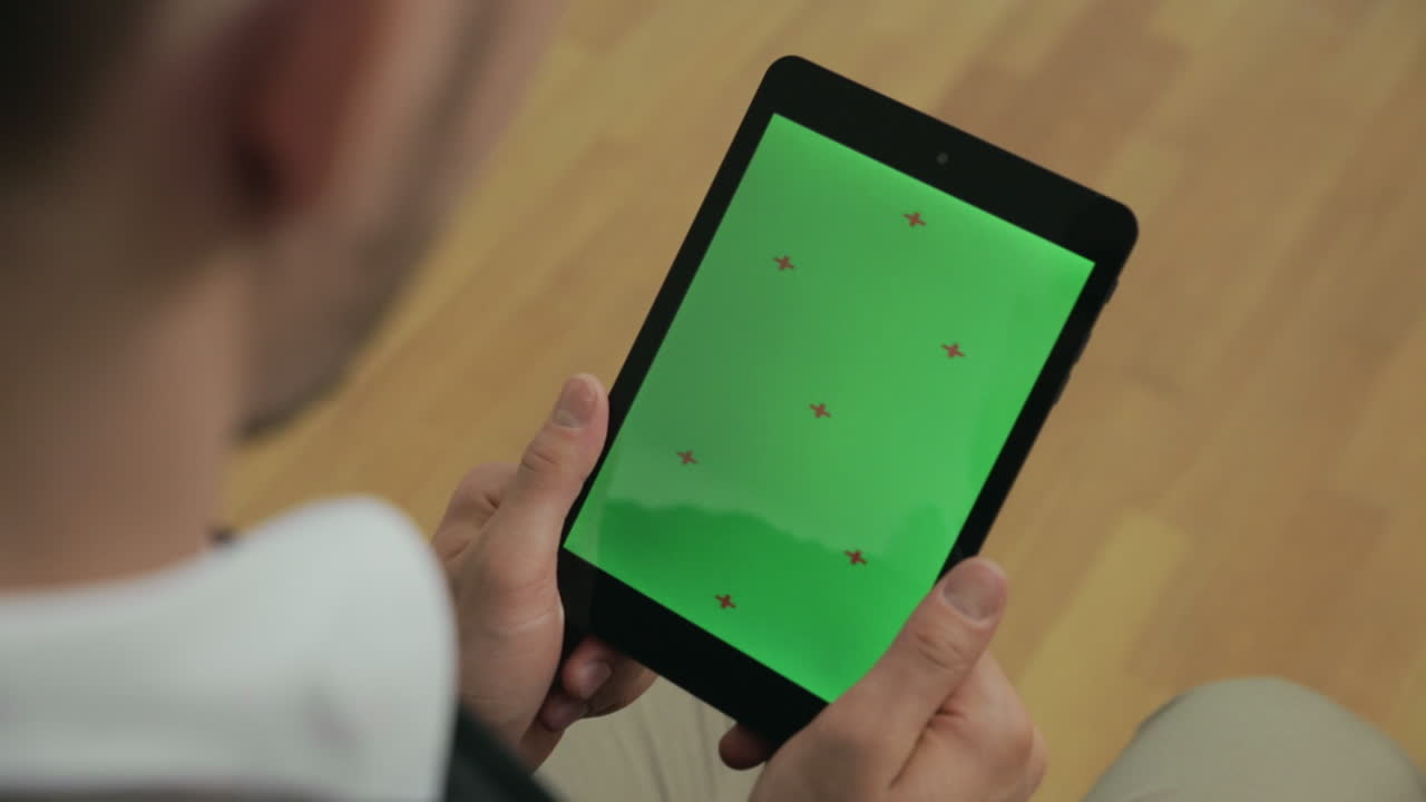 초록색 화면을 가진 태블릿을 들고 있는 청년. 태블릿을 보는 사업가