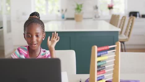 Video-of-happy-african-american-girl-smiling-waving-at-online-class-on-laptop-at-home,-copy-space
