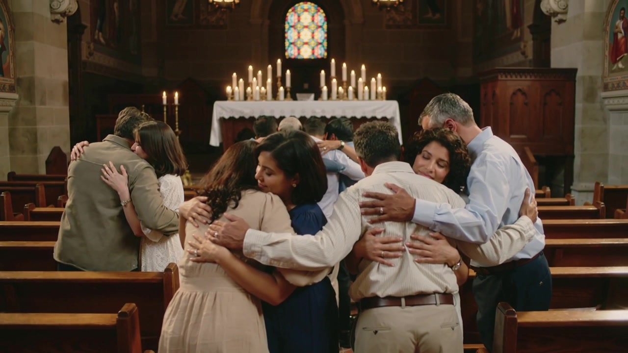 Turning congregants offering comfort in church aisle, wearing shirts and dresses, altar candles