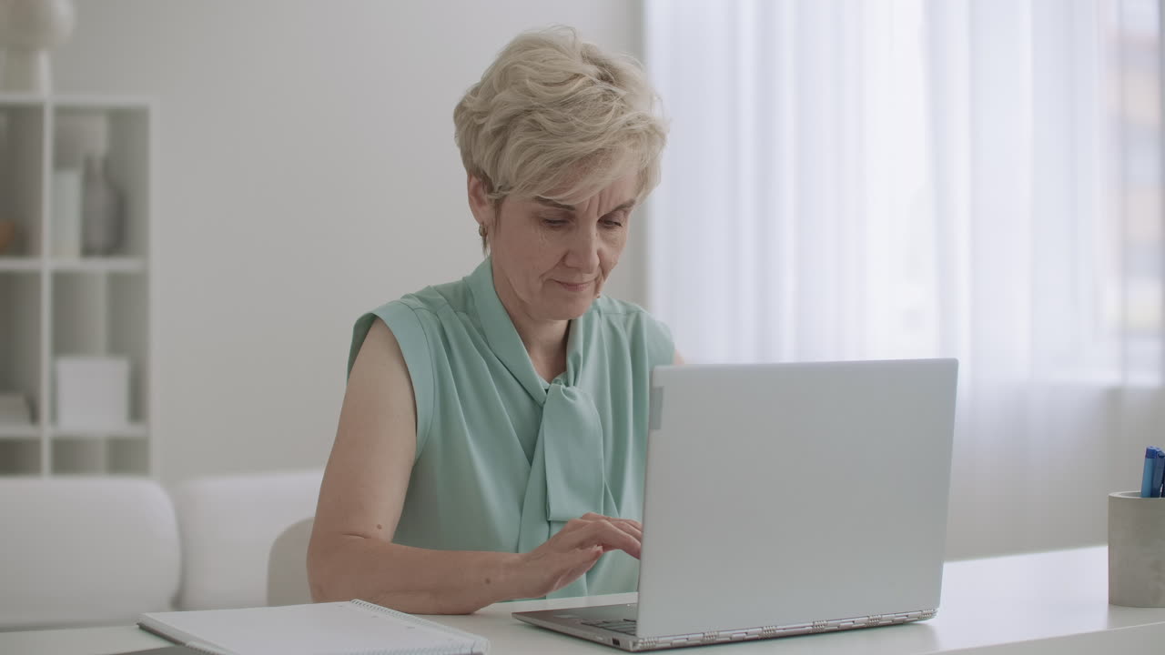 aged female accountant is working with laptop in office woman is typing on keyboard using internet