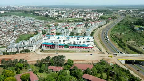 Aerial-backwards-shot-of-blocks-and-urban-slum-district-bordered-on-highway-road-during-sunlight