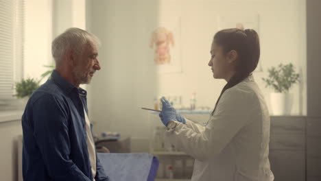 serious doctor checking senior patient throat in hospital. nurse examining man.