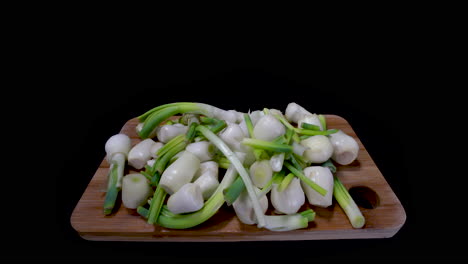 peeled onions on a wooden chopping board isolated in dark background. - pushin shot