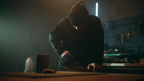 Wide-shot-of-skillful-woodworker-using-planer-to-perfectly-flatten-planks-in-his-workshop