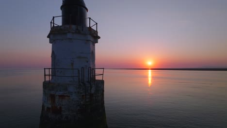 derelict lighthouse in very calm water at sunset. close reverse flyby. plover scar lighthouse, lancashire, uk.