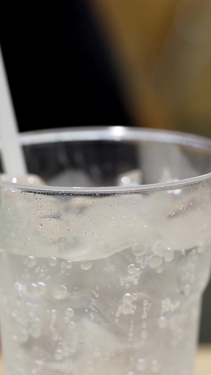 Bevanda gassata trasparente con ghiaccio e bollicine in un bicchiere di plastica
