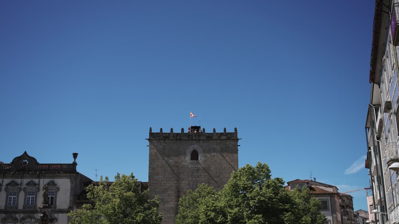 Historic stone tower in Barcelos, Portugal, with a flag on top and a clear blue sky