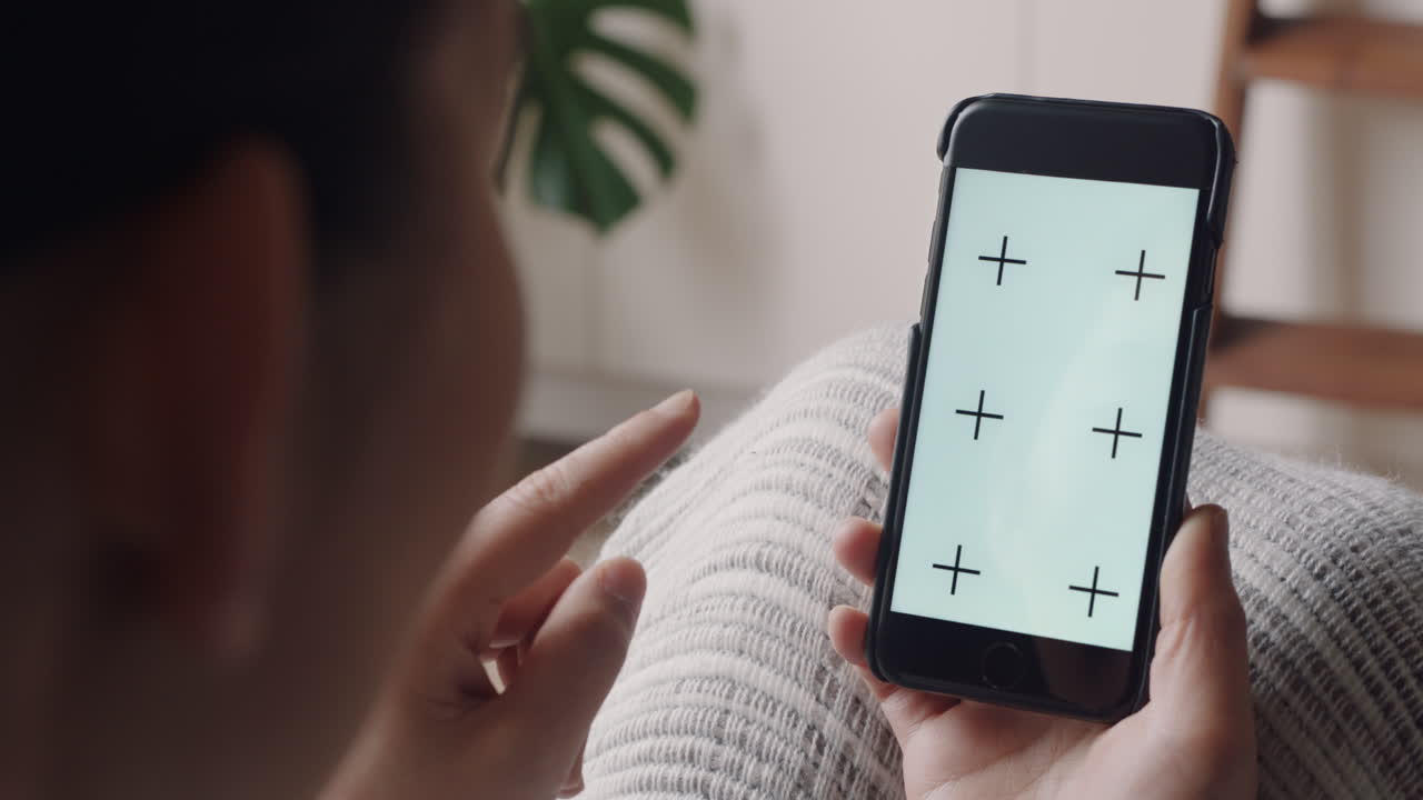 스마트폰을 사용하는 젊은 여성이 비디오 채팅을 하고 녹색 화면을 보고 휴대폰에서 채팅을 즐기고 있습니다. 크로마 키 디스플레이 수직 방향