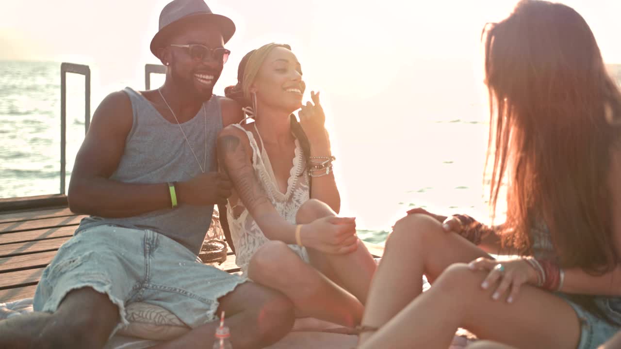 jóvenes amigos hipsters multiétnicos y parejas relajándose en el muelle