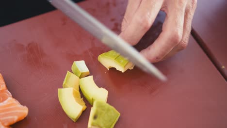 a professional chef cuts an avocado into small pieces, preparing a sushi dish, traditional japanese cuisine