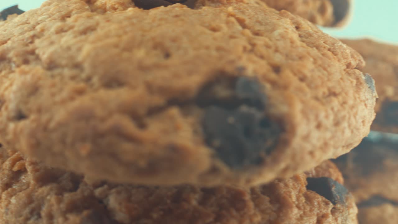 A macro close up shot of a white plate full of well baked chocolate chip cookies, on a 360 rotating stand, studio lighting, slow motion, 4K video