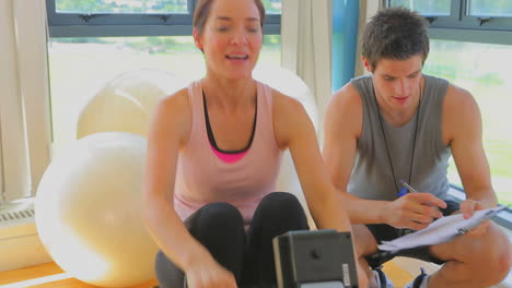 mujer feliz en la máquina de remo apoyado por un entrenador