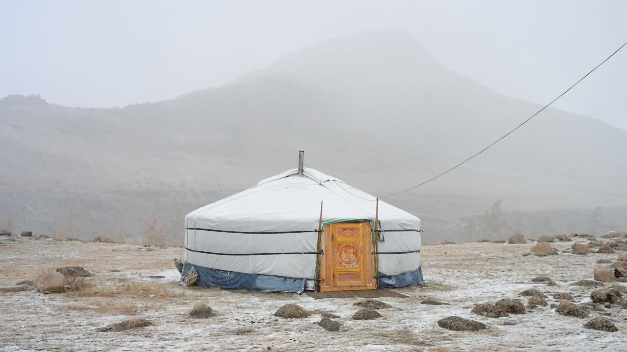 The first snow of autumn envelops a solitary Mongolian ger in a remote, misty mountain landscape. A powerful image of survival as winter's harsh conditions arrive