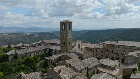 Aerial-pass-the-bell-tower-of-the-Chiesa-di-San-Donato-catholic-church-in-the-hilltop-village-of-Civita-di-Bagnoregio,-Province-of-Viterbo,-Italy