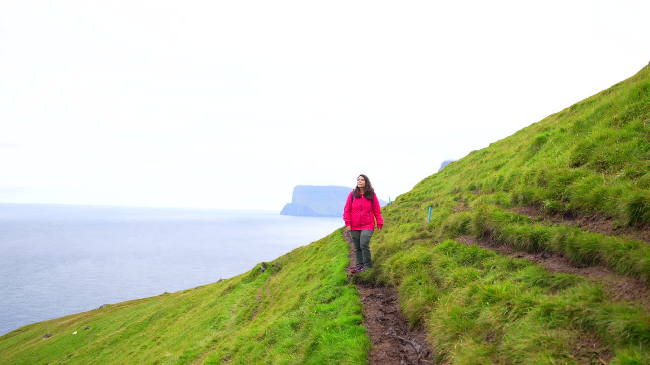 mujer admira el paisaje de las islas feroe en camino al faro de kallur, kalsoy