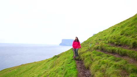 woman admires faroese landscape en route to kallur lighthouse, kalsoy