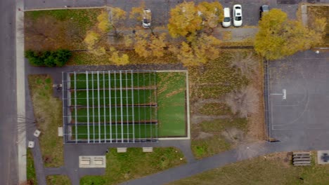 toma aérea volando directamente sobre una cancha de baloncesto y una jaula de bateo en un parque público de la ciudad